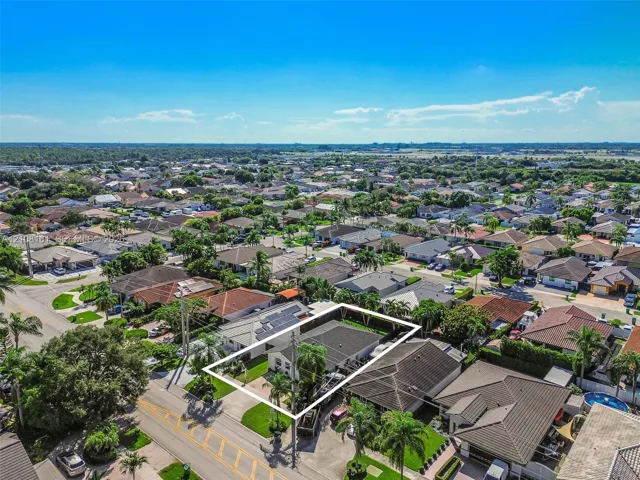 Aerial perspective of property featuring a fenced perimeter, solar panels, and manicured landscaping