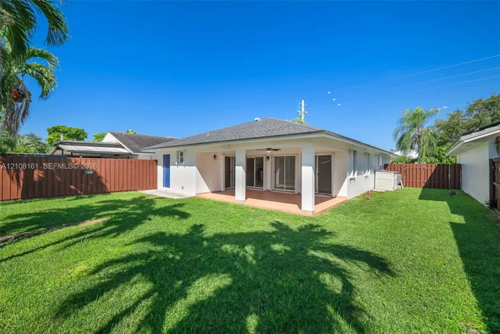Rear exterior featuring a covered patio, tiled flooring, sliding glass doors, and a fenced backyard