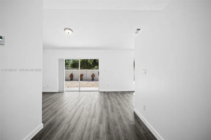 Wood-finish flooring, white walls, and glass sliding door providing exterior access to a fenced rear area