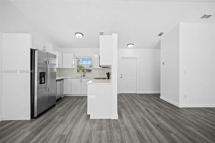 Kitchen featuring white cabinetry, wood-finish flooring, stainless steel side-by-side refrigerator, and a recessed window