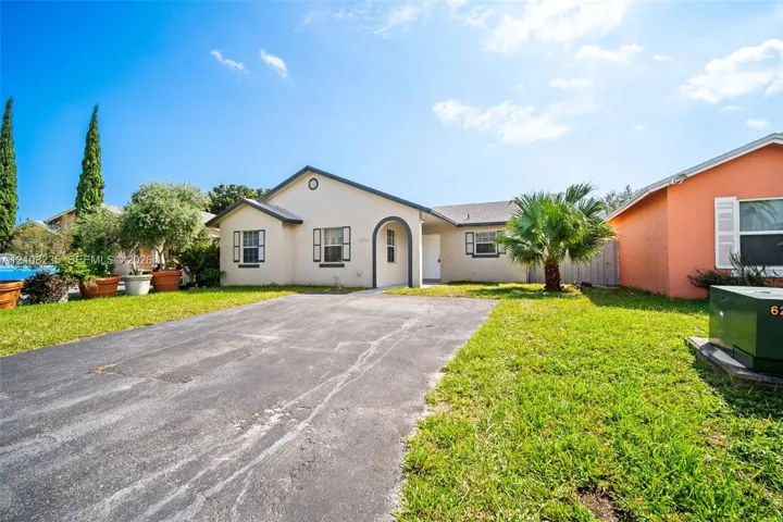Single-story residence featuring a stucco exterior, arched entryway, shingle roof, and asphalt driveway