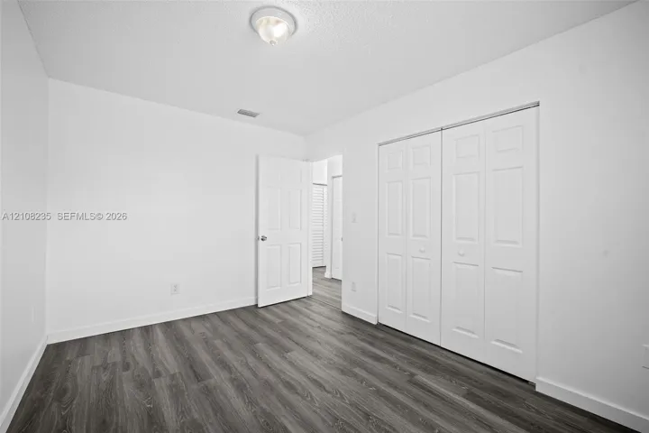 Neutral room featuring wood-finish flooring, double-panel closet doors, and a ceiling-mounted light fixture