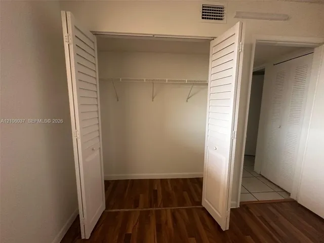 Closet featuring white louvered bifold doors, wood-finish flooring, and integrated wire shelving