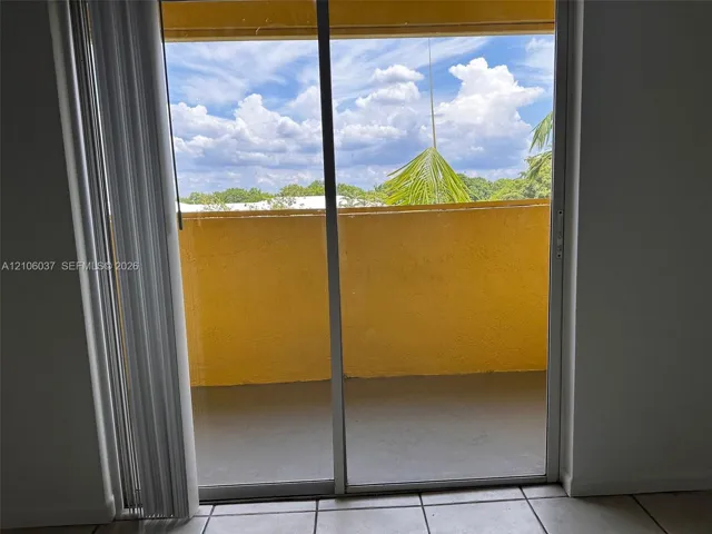 Sliding glass door opening to a private balcony with solid masonry railings and ceramic tile flooring