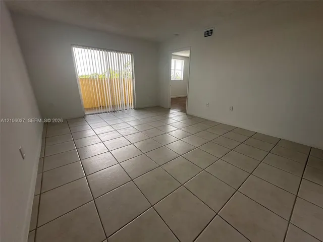 Interior room featuring large-format ceramic floor tile, sliding glass door with vertical blinds, and neutral wall tones