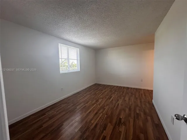 Interior space featuring wood-finish flooring, white walls, and a single-pane window with integrated blinds