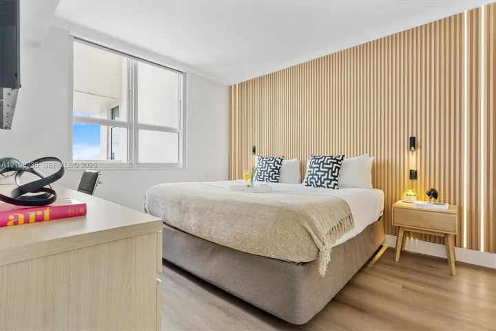 Bedroom featuring wood-slat accent wall paneling, integrated linear lighting, and wood-finish flooring