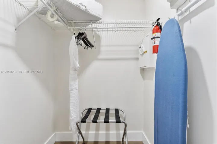 Walk-in closet featuring wire shelving, wall-mounted fire extinguisher, and built-in wall safe