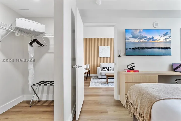 Interior space featuring wood-finish flooring, a built-in closet with wire shelving, and a custom built-in desk with integrated cabinetry
