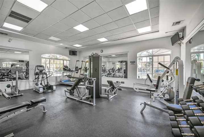 Fitness center featuring a drop ceiling with recessed panel lighting, rubberized flooring, and large wall-mounted​​‌​​​​‌​​‌‌​‌‌​​​‌‌​‌​‌​‌​​​‌​​ mirrors