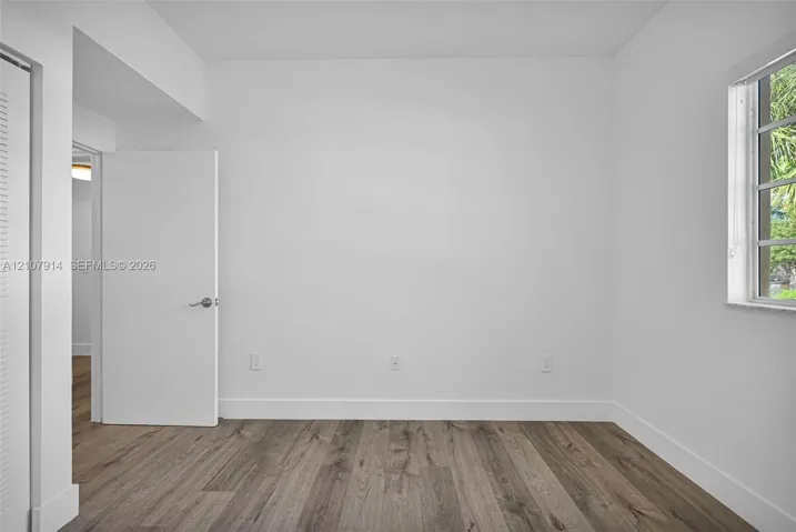 Interior space featuring wood-finish flooring, a multi-pane window, and white interior doors with brushed nickel hardware