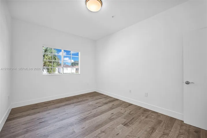 Room featuring wood-finish flooring, a multi-pane window, and a flush-mount ceiling fixture