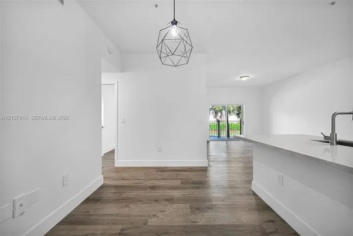 Wood-finish flooring throughout, geometric pendant lighting, stone-surface kitchen island, and metal-finish gooseneck faucet