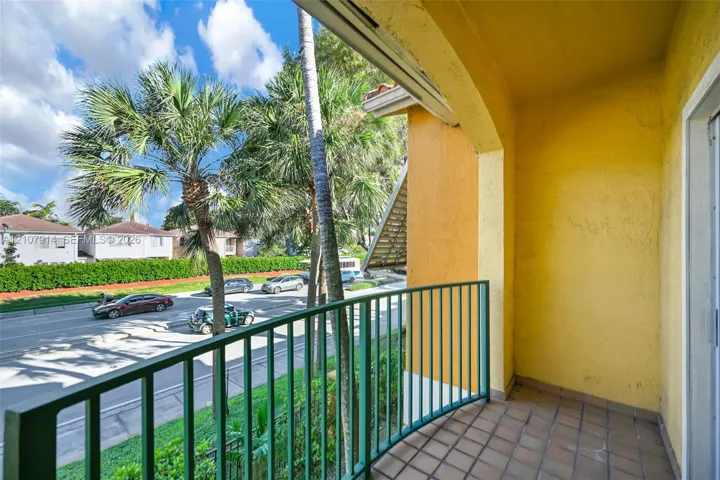 Covered balcony featuring tile flooring, an arched ceiling, and a green metal railing
