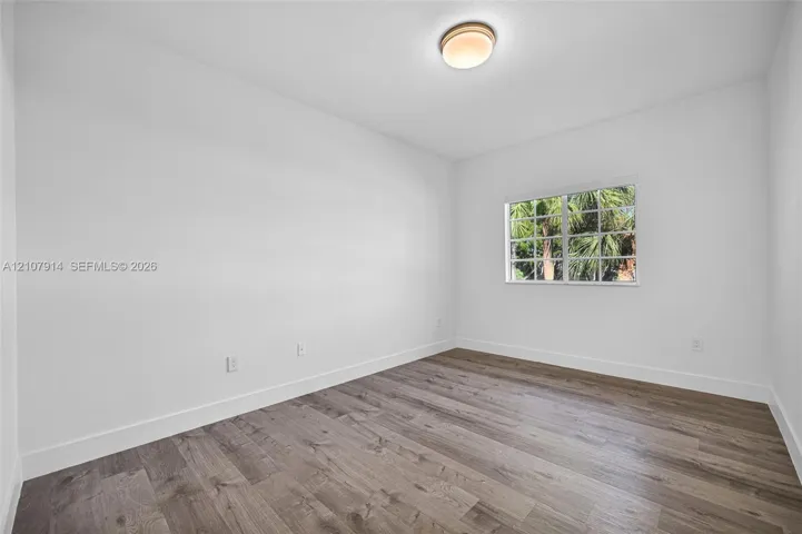 Neutral-toned room featuring wood-finish flooring, a multi-pane window, and a flush-mount dome light fixture