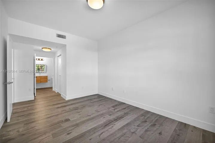 Neutral-toned interior space featuring wood-finish flooring, crisp white walls, and flush-mount ceiling light fixtures