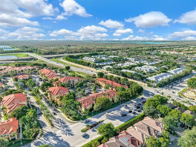 Aerial perspective of a multi-building residential development featuring terracotta-style tile roofs, mature canopy trees, paved thoroughfares, and manicured landscaping