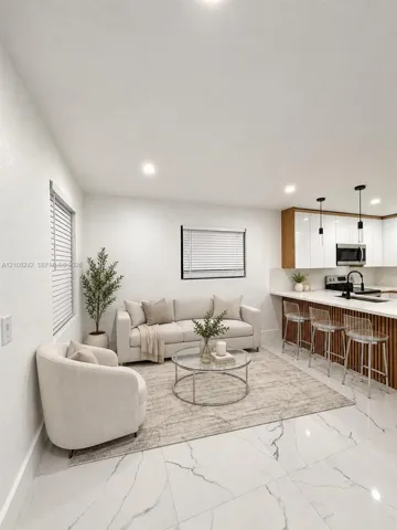 Kitchen area featuring white gloss cabinetry, vertical wood-slat island paneling, stone-finish countertops, recessed lighting, and large-format tile flooring