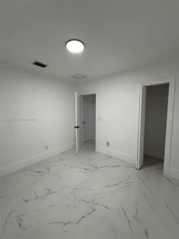 Interior space featuring polished stone-finish flooring with marbled veining and a flush-mount ceiling light fixture