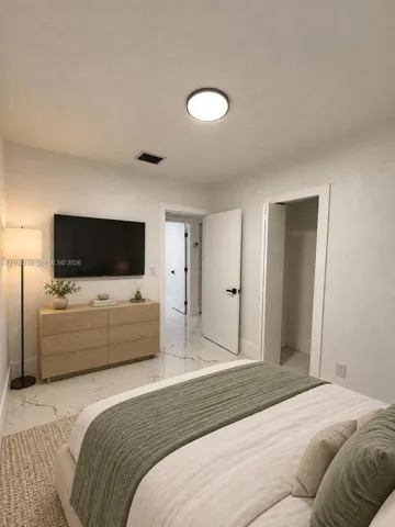 Neutral-toned interior featuring large-format stone-finish tile flooring with veining, round flush-mount ceiling lighting, and solid-core doors with matte black hardware