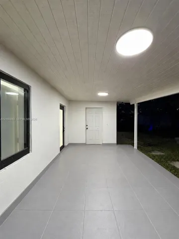 Covered patio featuring large-format grey tile flooring, tongue-and-groove ceiling paneling, and flush-mount LED lighting