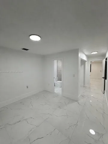 Large-format stone-finish flooring with high-gloss surfacing and flush-mount ceiling light fixtures