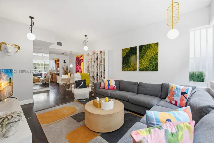Living area featuring wood-finish flooring, floor-to-ceiling built-in shelving, and custom pendant light fixtures