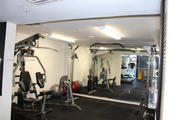 Dedicated fitness area featuring wall-to-wall mirrors, recessed linear lighting, and resilient rubberized flooring