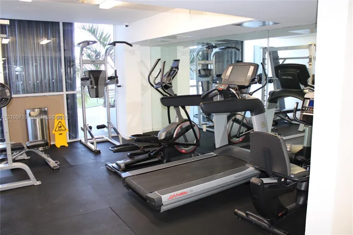 Fitness center featuring rubber flooring, floor-to-ceiling mirrored walls, and floor-to-ceiling windows