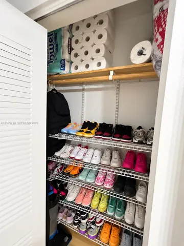 Storage closet featuring tiered wire shelving and a finished wood top shelf