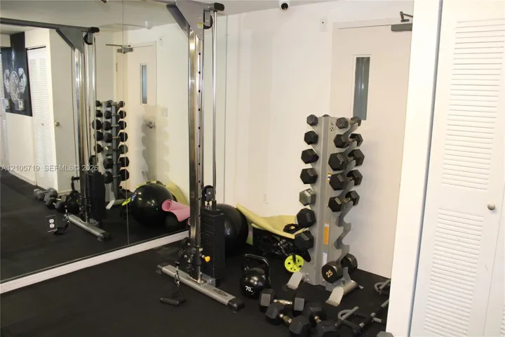 Full-wall mirror, solid rubber flooring, and louvered-panel closet doors