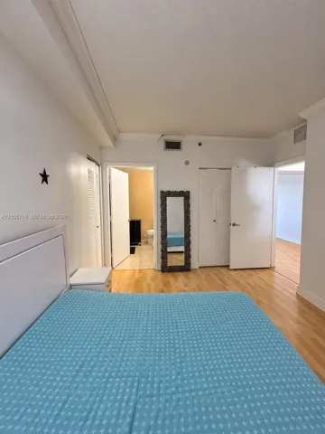 Room featuring wood-finish flooring, crown molding, and double-door closets