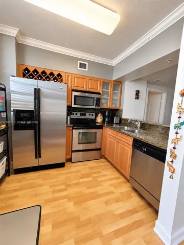 Kitchen featuring wood cabinetry with integrated wine storage, stainless steel appliances, stone countertops, double-basin sink, and wood-finish flooring