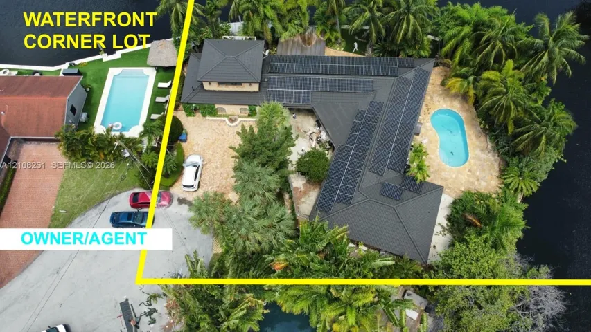 Waterfront corner lot featuring a private pool with paved surround and integrated solar panel array