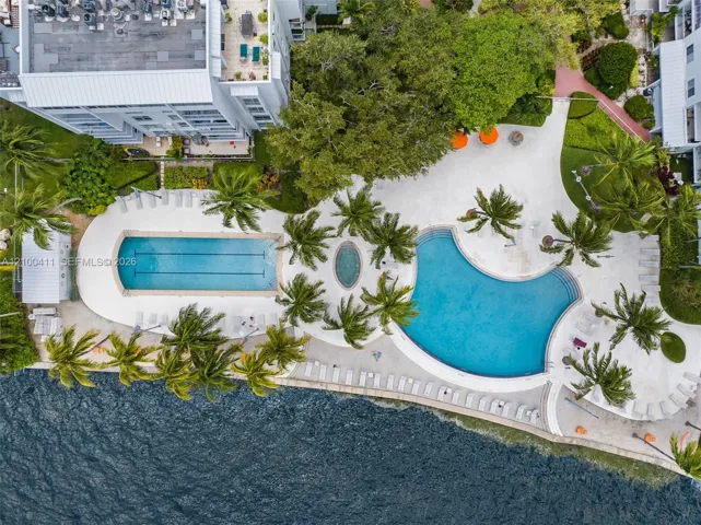 Waterfront community amenities featuring a lap pool, a free-form pool, a spa, expansive sun decks, and mature tropical landscaping