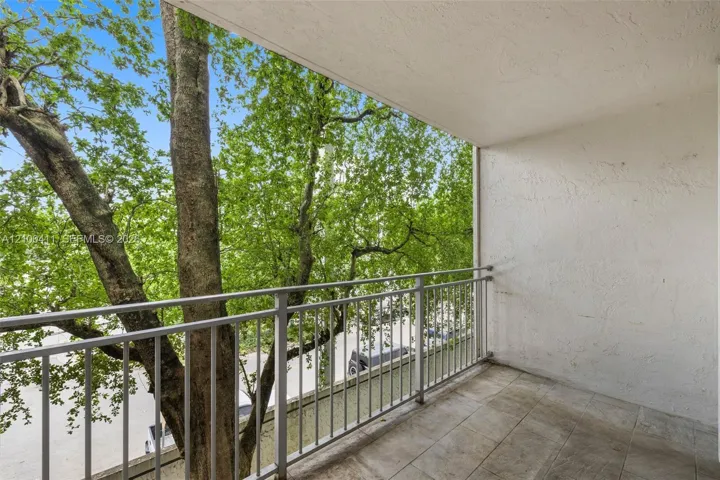 Covered balcony featuring neutral ceramic tile flooring, textured plaster walls, and a metal railing