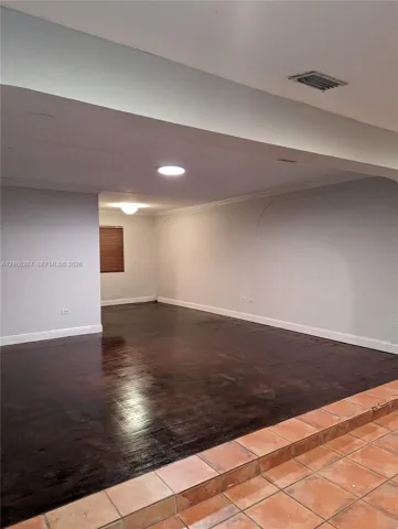 Sunken living area featuring dark wood-finish flooring, terra cotta tile steps, recessed ceiling lighting, and arch-top wall detailing