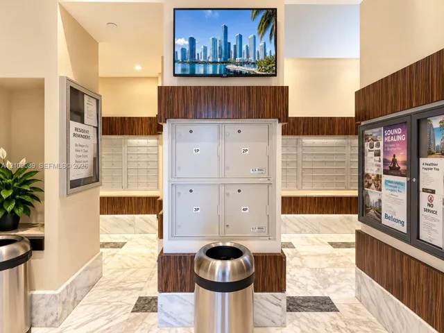 Mail center area featuring integrated parcel lockers, wood-finish wall paneling, and stone tile flooring
