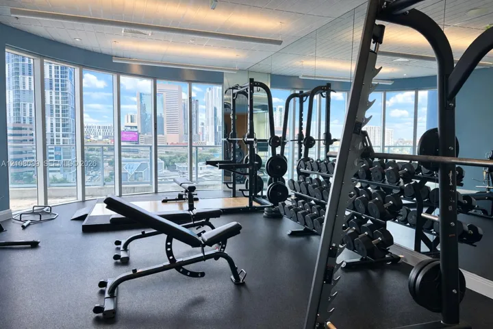 Fitness center featuring floor-to-ceiling windows, panoramic urban scenery, and mirrored walls