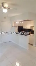 Pass-through kitchen featuring white cabinetry, a breakfast bar, and tile flooring throughout