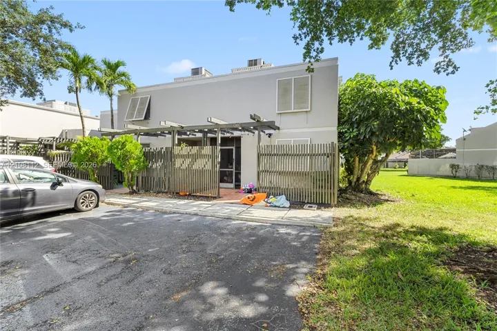Two-story exterior featuring a pergola, fenced patio, paved walkway, and white louvered shutters