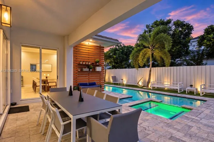 Covered patio with paver flooring, horizontal slat wood accent wall, built-in shelving, swimming pool with integrated spa, and vertical privacy fencing