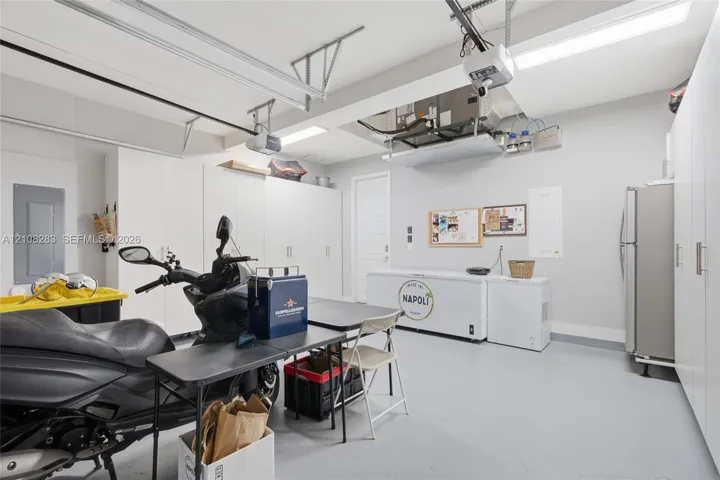 Garage space featuring extensive wall-to-wall built-in cabinetry, epoxy-finished flooring, and overhead lighting