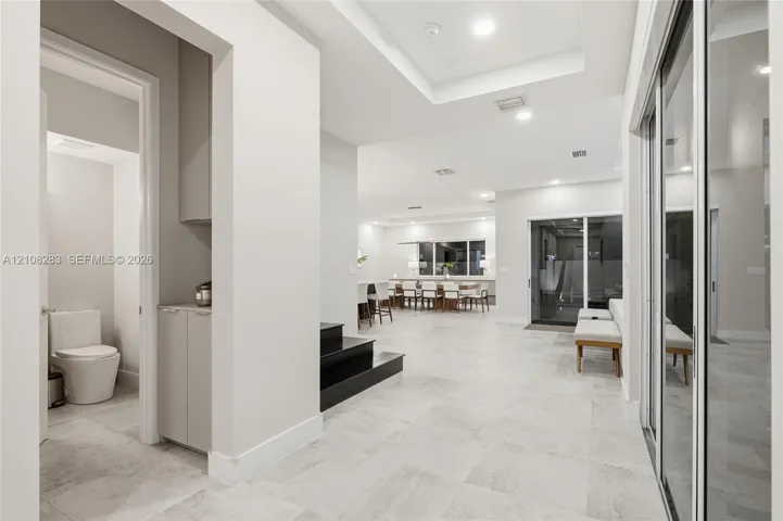 Interior space featuring large-format tile flooring, recessed ceiling lighting, tray ceilings, built-in cabinetry, and sliding glass doors