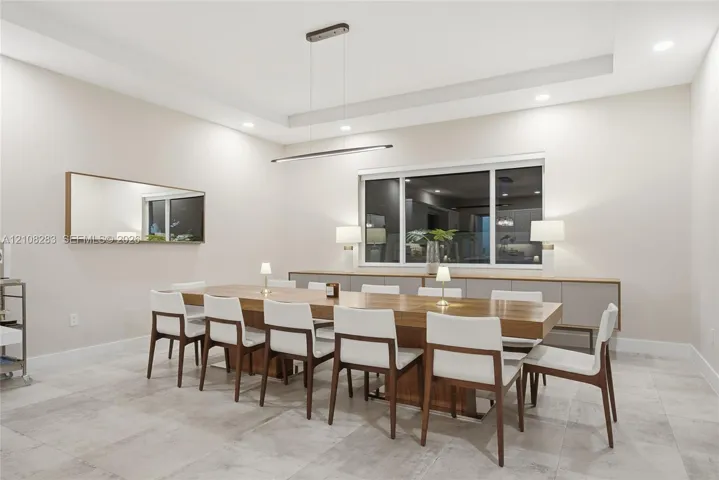 Tray ceiling with recessed lighting, linear pendant fixture, large-format tile flooring, and built-in cabinetry featuring a smooth countertop