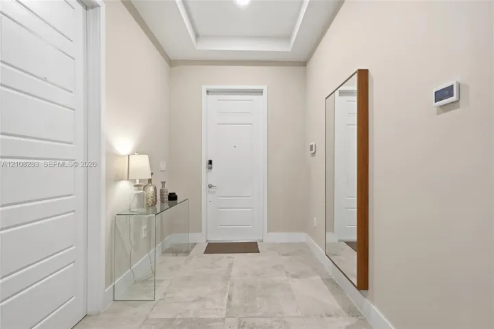 Entryway featuring large-format tile flooring, a tray ceiling, and a paneled entry door