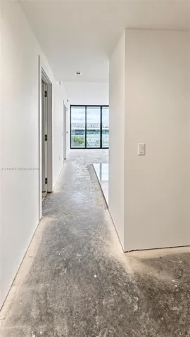 Interior hallway featuring floor-to-ceiling black-framed glass panels, recessed ceiling lighting, and polished stone tile flooring