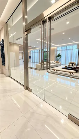 Floor-to-ceiling glass partition featuring polished metal hardware, expansive ceramic tile flooring, recessed ceiling lighting, and full-height windows