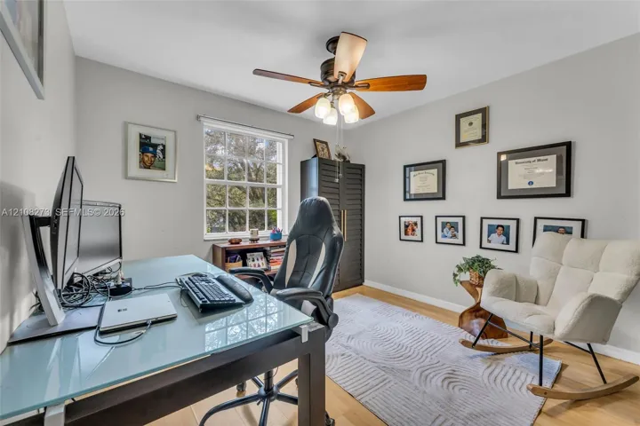 Room featuring wood-finish flooring, a multi-light ceiling fan, and a grid-style window