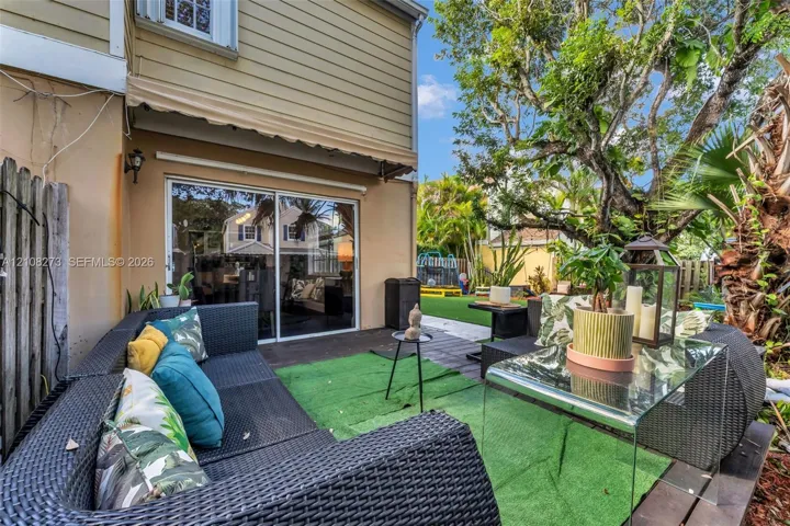 Rear patio featuring dark-tone wood-finish decking, retractable fabric awning, and sliding glass doors